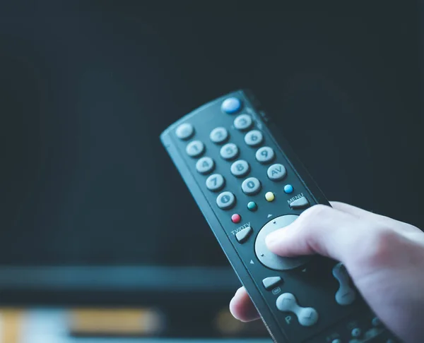Male hand is holding TV remote control, streaming on a smart TV. — Stock Photo, Image