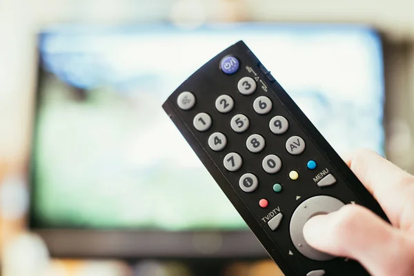 Male hand is holding TV remote control, streaming on a smart TV. — Stock Photo, Image