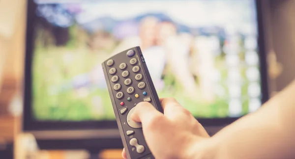 Mannenhand houdt Tv remote control afstandsbediening,, streaming op een smart Tv. Stockafbeelding