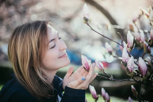 Menina bonita está cheirando flores de magnólia na primavera, Salzburgo , — Fotografia de Stock