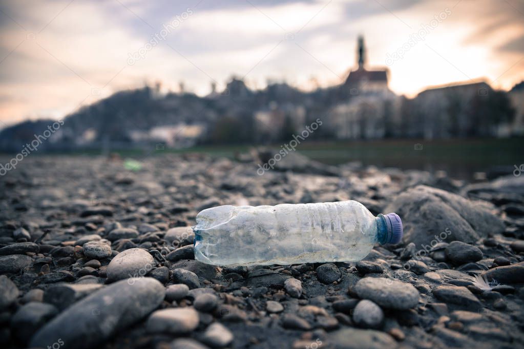 Environmental pollution: plastic bottle on the beach, urban city