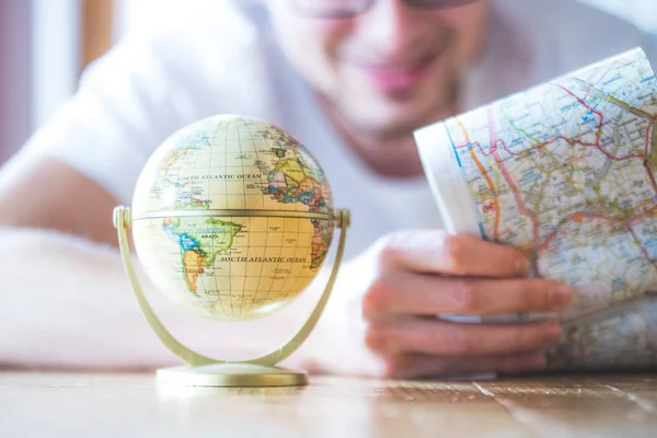 Planificación del próximo viaje: Hombre con mapa y globo en miniatura en t — Foto de Stock