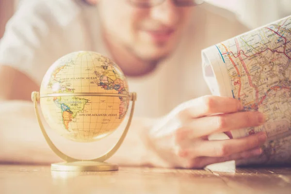 Planificación del próximo viaje: Hombre con mapa y globo en miniatura en t — Foto de Stock