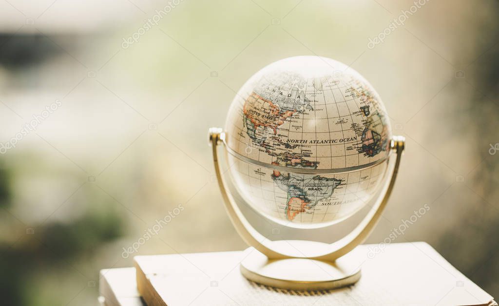 Planning the next journey: Miniature globe on a stack of books.