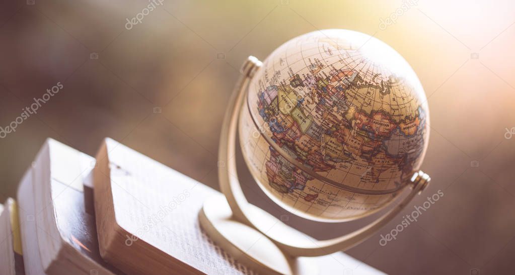 Planning the next journey: Miniature globe on a stack of books.