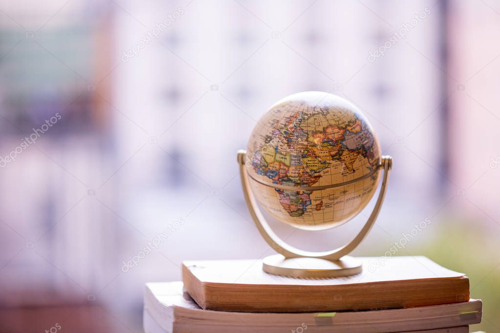 Planning the next journey: Miniature globe on a stack of books.