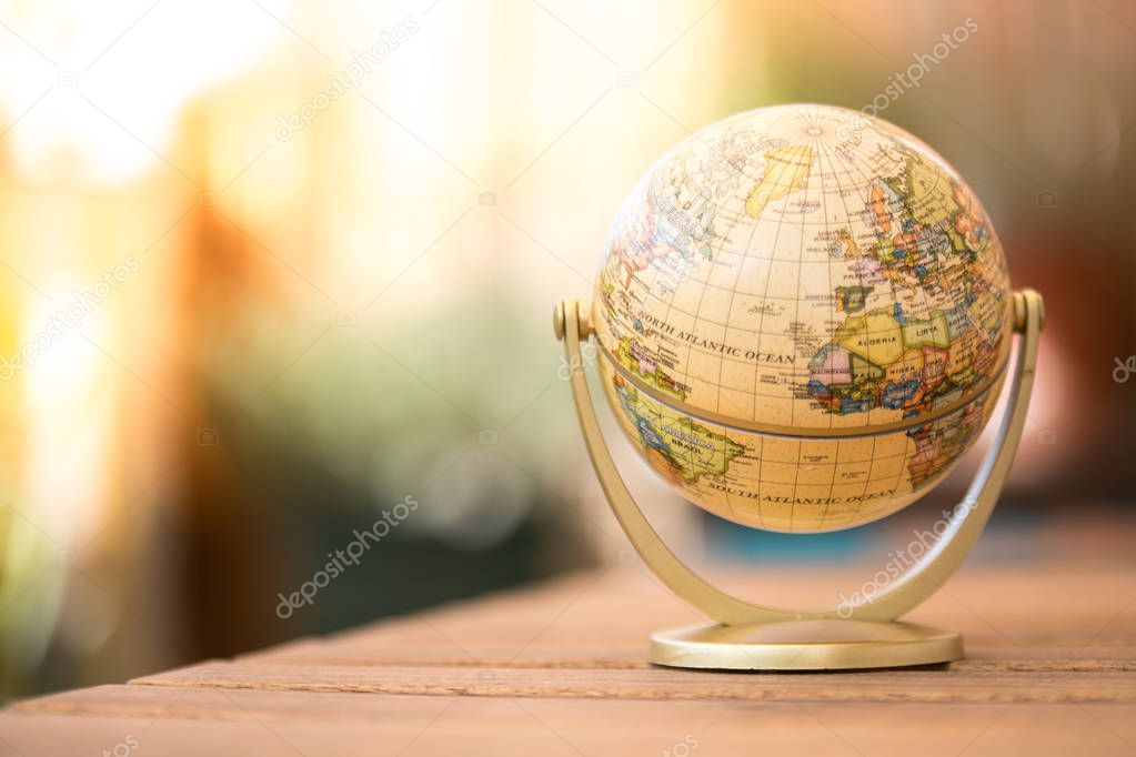 Miniature globe model on a rustic wooden table. Symbol for trave