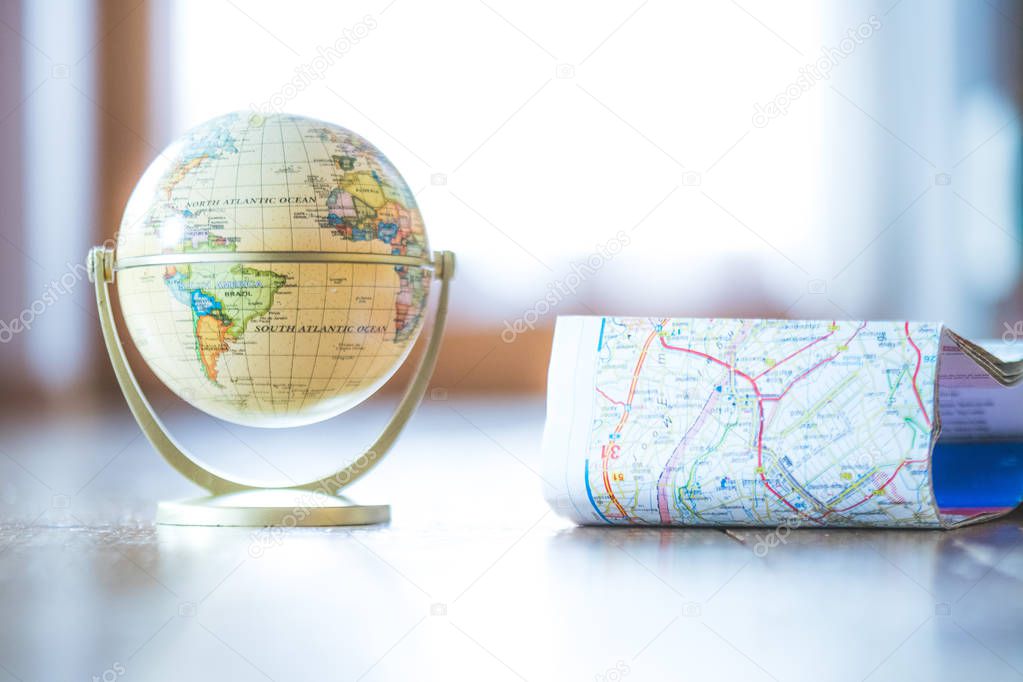 Miniature globe model on a rustic wooden table. Symbol for trave