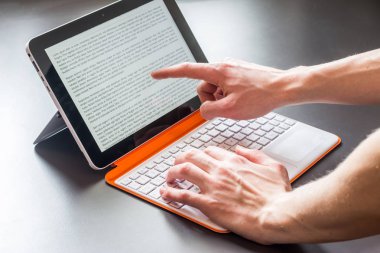 Genç adam bir beyaz turuncu convertible dizüstü bilgisayarda çalışıyor