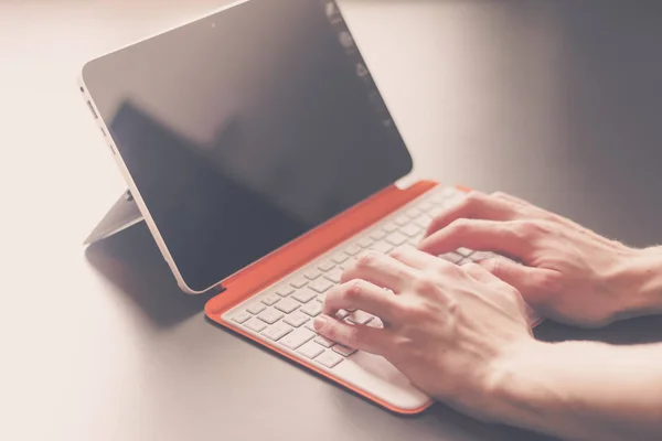 Jovem está trabalhando em um laptop conversível laranja branco — Fotografia de Stock