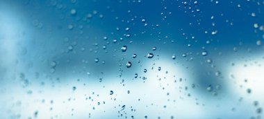 Pencere, mavi gökyüzü ve bulutlar bulanık bac içinde su damlaları