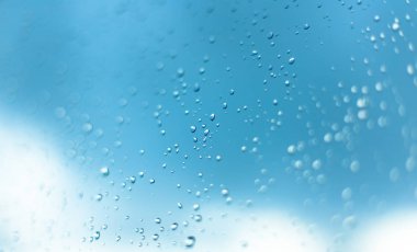 Pencere, mavi gökyüzü ve bulutlar bulanık bac içinde su damlaları