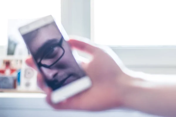 Telefone inteligente na mão, reflexo de uma cara no displ preto — Fotografia de Stock