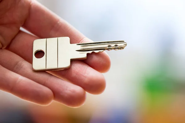 Προχωρώντας σε ένα νέο σπίτι: Κλείστε ένα χέρι κρατώντας ένα κλειδί. Κατάλληλη — Φωτογραφία Αρχείου