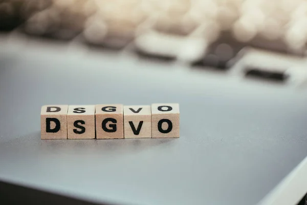 DSGVO : Des cubes en bois avec des lettres Montréal.DSGVO Montréal couché sur un ordinateur portable . — Photo