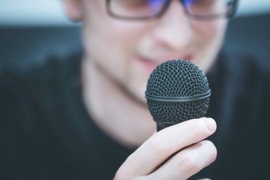 Mikrofonda konuşan: bulanık yüz ile genç adam alıyor