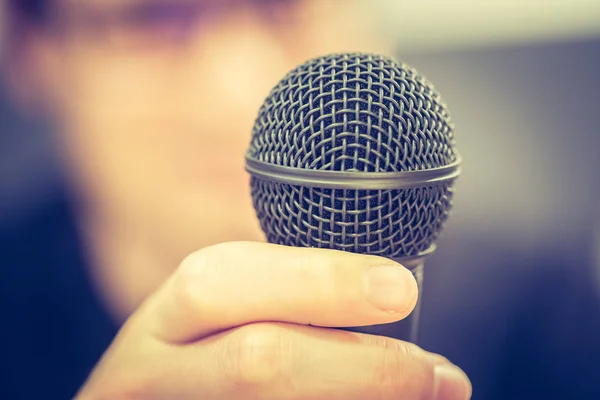 Speaking in the microphone: Young man with blurry face is taking — Stock Photo, Image