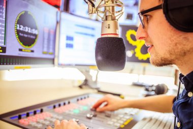 Radyo moderatör modern bir yayın stüdyosunda oturuyor ve t
