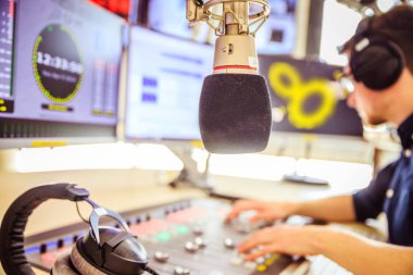 Radyo moderatör modern bir yayın stüdyosunda oturuyor ve t