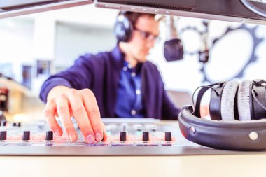 Radyo moderatör modern bir yayın stüdyosunda oturuyor ve t