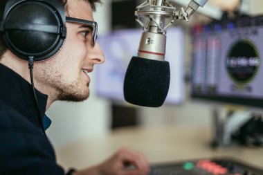 Radyo moderatör modern bir yayın stüdyosunda oturuyor ve t