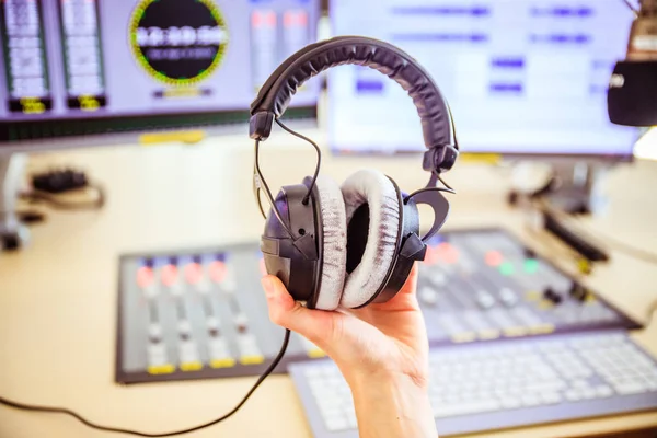 Young man holds headphones in the recording studio. Buttons, stu — Stock Photo, Image