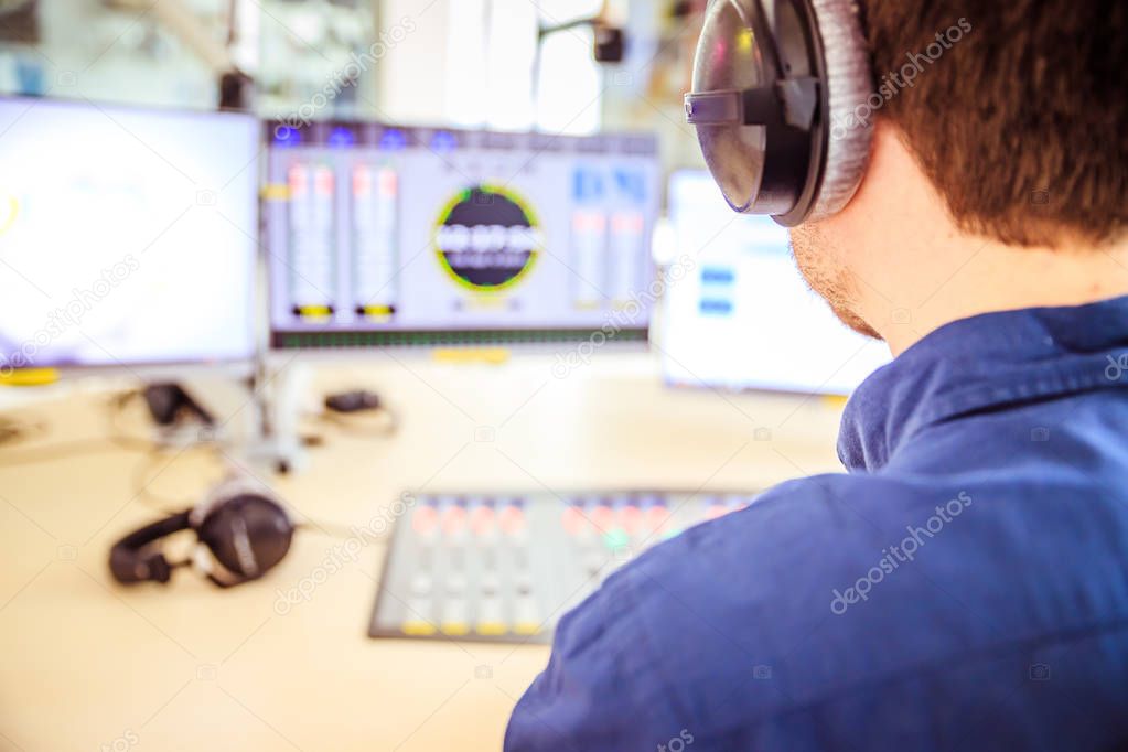 Radio moderator is sitting in a modern broadcasting studio and t