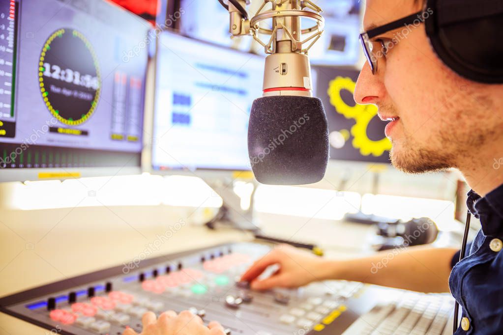 Radio moderator is sitting in a modern broadcasting studio and t