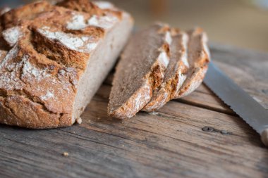 Rustik ahşap kesme tahtası üzerinde dilimler halinde taze ekmek ve bıçak, 