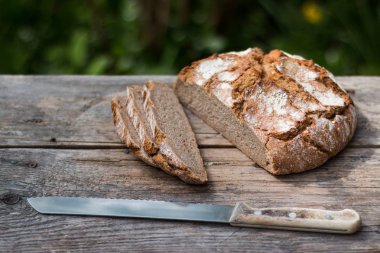 Rustik ahşap kesme tahtası üzerinde dilimler halinde taze ekmek ve bıçak, 