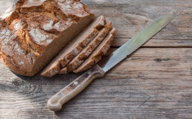 Rustik ahşap kesme tahtası üzerinde dilimler halinde taze ekmek ve bıçak, 