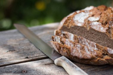 Rustik ahşap kesme tahtası üzerinde dilimler halinde taze ekmek ve bıçak, 