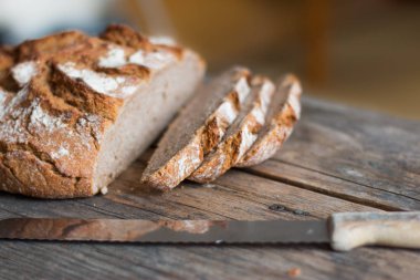 Rustik ahşap kesme tahtası üzerinde dilimler halinde taze ekmek ve bıçak, 
