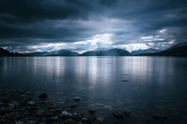 İskoçya'da mistik manzara göl sahne: Bulutlu gökyüzü, güneş ışınları 