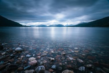 İskoçya'da mistik manzara göl sahne: Bulutlu gökyüzü, güneş ışınları 