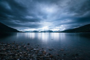 İskoçya'da mistik manzara göl sahne: Bulutlu gökyüzü, güneş ışınları 