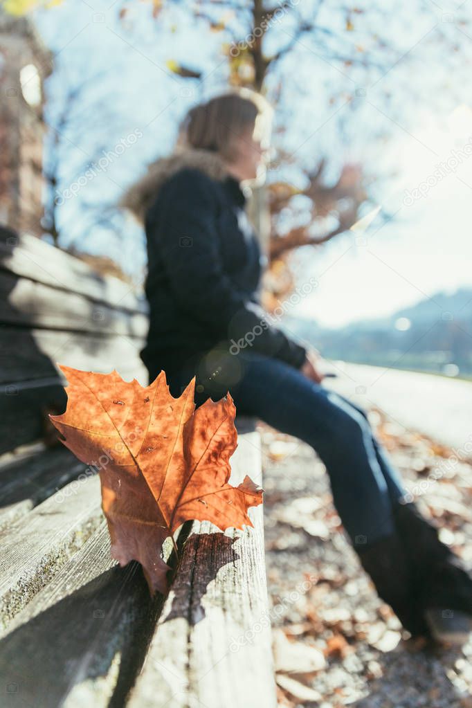 Woman is sitting on a park bench, autumn