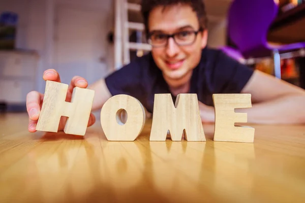 Nuevo Hogar: El hombre está arreglando las letras HOME — Foto de Stock