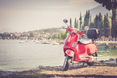 İtalyan Yaşam Tarzı: Kırmızı scooter, mavi gökyüzü ile costal manzara. 