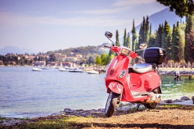 İtalyan Yaşam Tarzı: Kırmızı scooter, mavi gökyüzü ile costal manzara. 