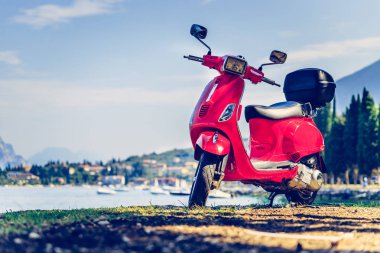 İtalyan Yaşam Tarzı: Kırmızı scooter, mavi gökyüzü ile costal manzara. 