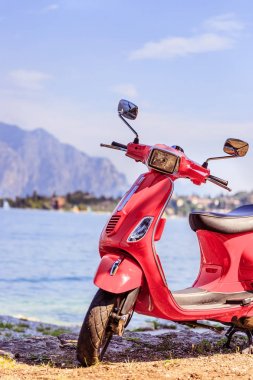 İtalyan Yaşam Tarzı: Kırmızı scooter, mavi gökyüzü ile costal manzara. 