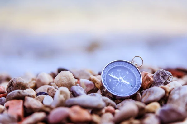 Navigation concept: Compass is lying on the beach near the sea