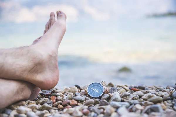 World travel concept: Male feet and compass on the beach near th — Stock Photo, Image