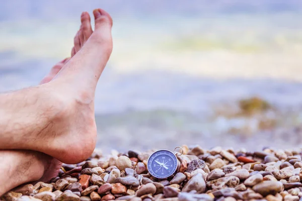 World travel concept: Male feet and compass on the beach near th — Stock Photo, Image