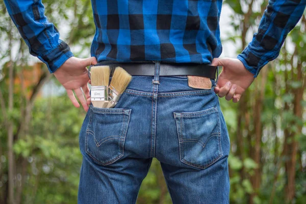 Ev tamircisi: Merhaba boya fırçaları ile genç bir adamın arka görünümü