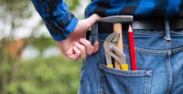 Home handyman: Rear view of a young man with hammer, pencil and — Stock Photo, Image