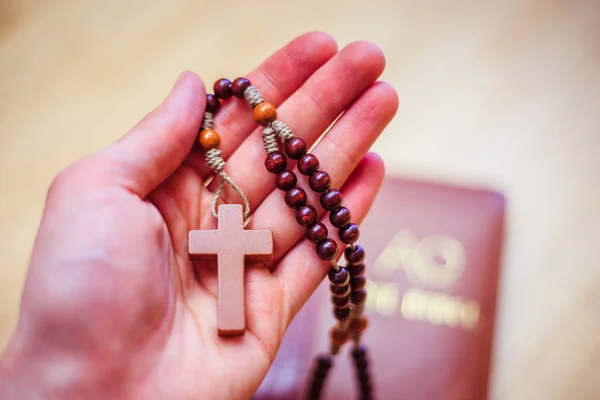 O homem está orando: Rosário nas mãos, Bíblia sagrada no backgroun — Fotografia de Stock