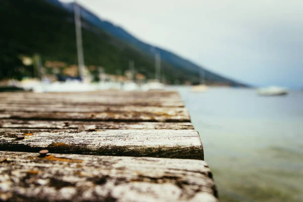 Muelle de madera que se extiende sobre el agua azul del lago y las montañas, b — Foto de Stock