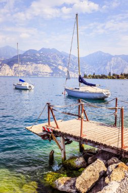 Yelken: Ahşap rıhtım iskelesi, arka planda yelkenli tekneler.